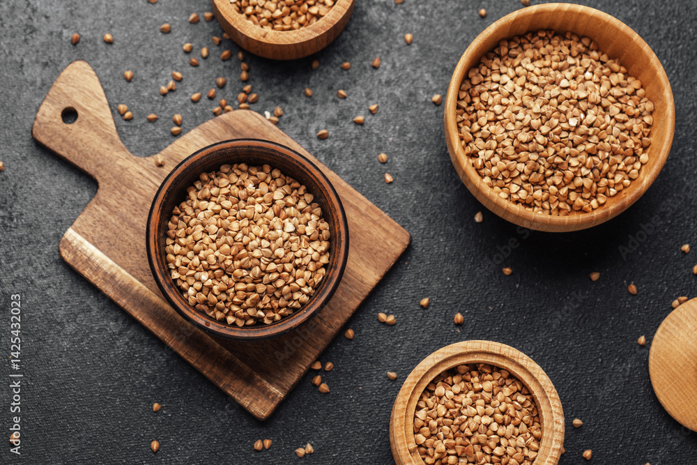 Buckwheat grains arranged artistically on wooden bowls and board in a kitchen Buckwheat grains arranged artistically on wooden bowls and board in a kitchen