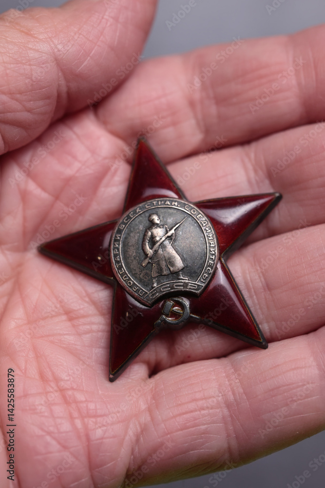 Vertical Macro Close Up Of The Soviet Military Order Of The Red Star With Soldier Figure, Held In A Person's Hand. Ussr Award History And Memorabilia. Vertical Macro Close Up Of The Soviet Military Order Of The Red Star With Soldier Figure, Held In A Person's Hand. Ussr Award History And Memorabilia.