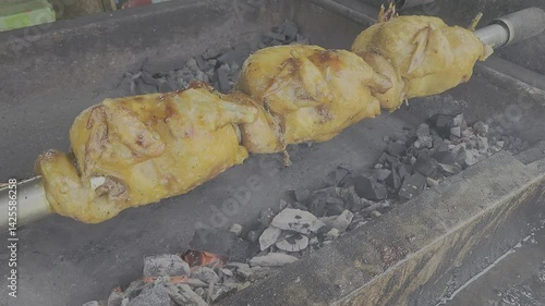 Grill chicken over hot charcoal, rotating grilled chicken street food in thailand