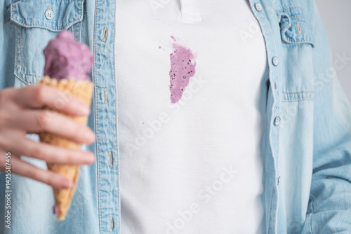 Close up melting purple ice cream in waffle cone in the background dirty stain on white clothes. Space for text. Concept of daily stains on clothes