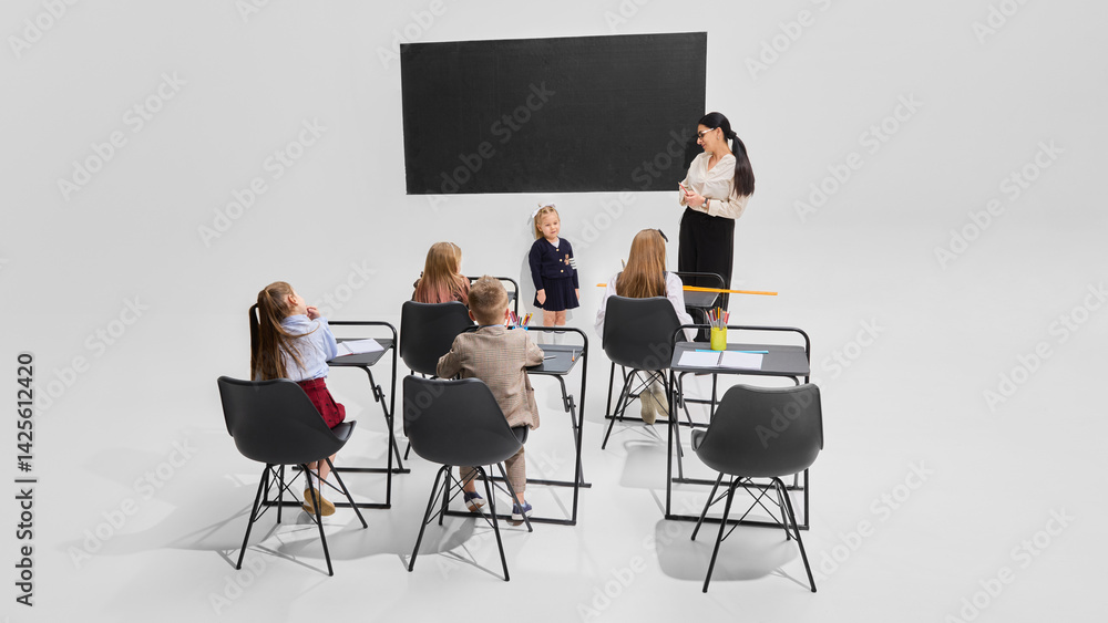 Fototapeta premium Cheerful girl presenting in front of classmates with teacher watching, full of confidence. Concept of education, school speech, individual achievement, classroom dynamics, learning development.
