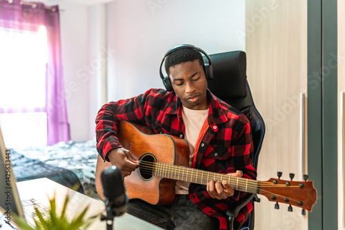 Young musician composing music playing acoustic guitar at home