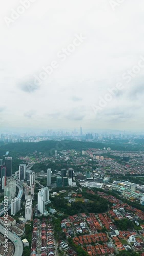 Wallpaper Mural Vertical expansive aerial view of Kuala Lumpur and Petaling Jaya cityscape under a cloudy sky, showing urban density, high-rise buildings, residential zones, and surrounding hills. UHD. Malaysia Torontodigital.ca
