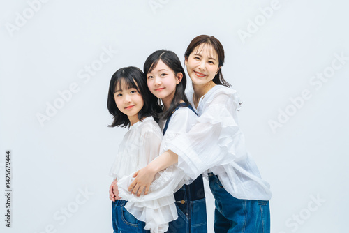 Obraz na płótnie 親子、子供、人物、女子、女性、女の子、家族、ハグ、ファミリー、ファッション、カジュアル、リラックス、子育て、育児、笑顔、ポートレート、デニム、ジーンズ、おしゃれ、シンプル、キレイめ、美容、スキンケア、健康、ヘルシー、コーデ、ママ、母親、姉妹、少女、母子、母娘、成長、小学生、モデル、寄り添う、守る、保険、安心、安全、保護者、白バック、コピースペース、広告、家庭、写真館、キッズ、フォトスタジオ、日本人 w salonie