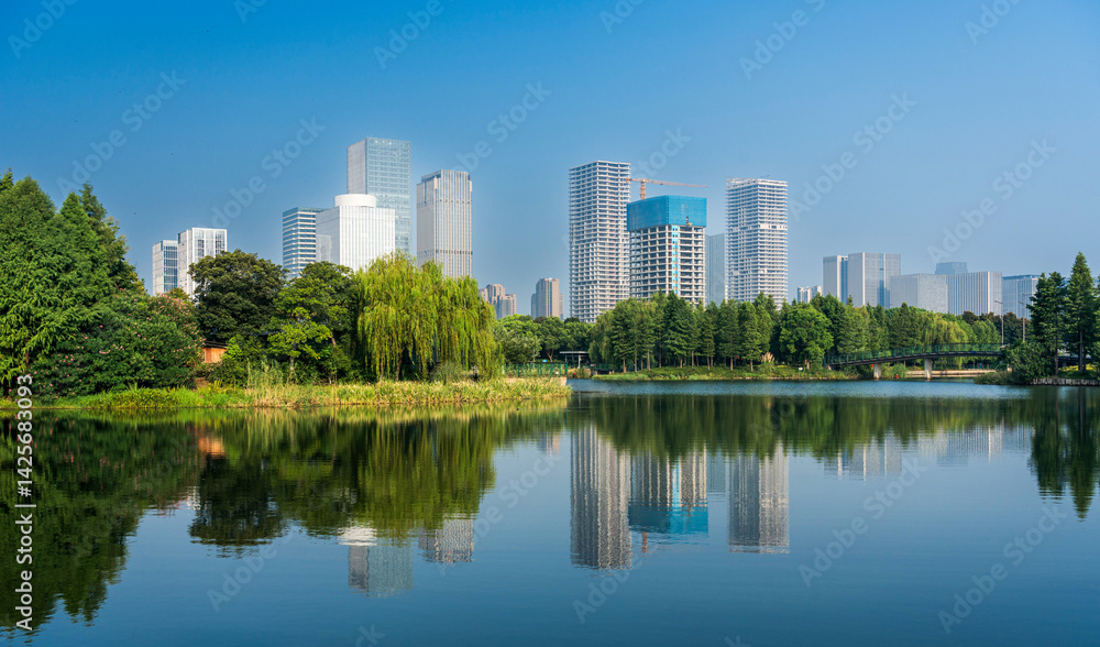 Naklejka premium Serene Urban Oasis: A Stunning Reflection of City Life on Quiet Waters