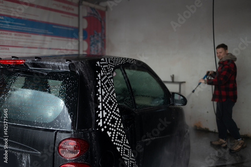 Car washing outdoors. Car washing with soap and high pressure water. Wheel alloy cleaning at car wash station with foam and high pressure water jet. Washing rims. High quality photo