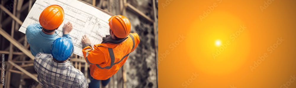 Top view of architects and engineers wearing orange helmets working on a construction site with blueprints. teamwork, planning, and building concept with ample copy space