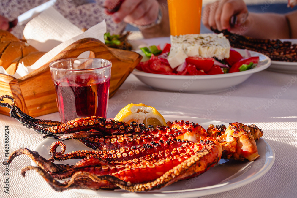 Grilled octopus served with lemon, accompanied by drinks.