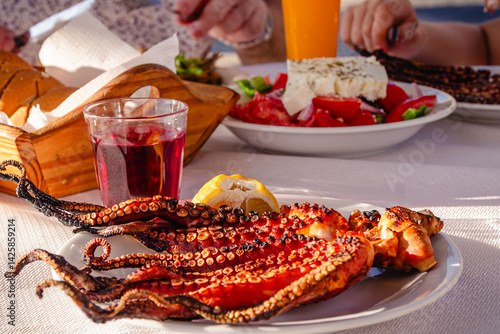 Obraz na płótnie Grilled octopus served with lemon, accompanied by drinks. w salonie