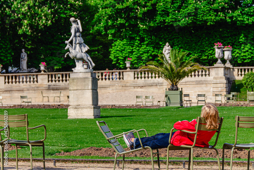 Woman lying  on chairs and resting out in the garden, Paris, France.