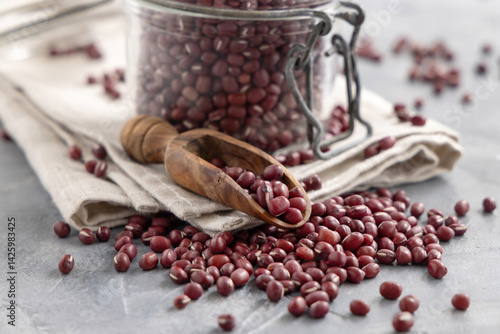 Glass jar full of dried azuki beans with a wooden scoop closeup. Vegetarian protein source