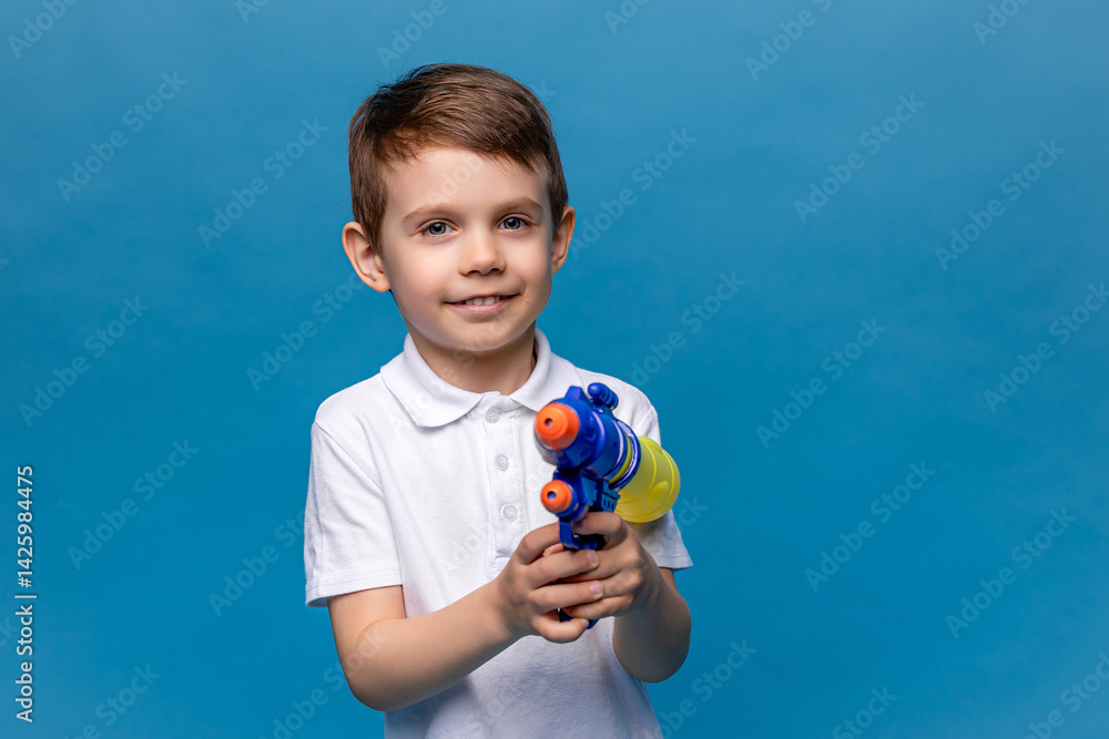Laughing child boy playing with water gun toy on blue background. Pool toys and water fun for family with children. Summer vacation with kids. Active outdoor sport for preschooler