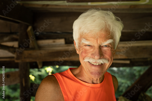 Positive casual dressed gray-haired handsome senior man looking straight into the camera lens - Eye contact - Portrait - Happy elderly lifestyle concept without age limits