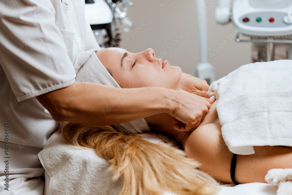 Obraz premium Satisfied mature adult woman receiving professional face and neck massage in beauty spa or salon. Modern cosmetics and beauty concept.