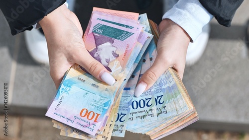 Billede på lærred Woman clutching worthless venezuelan bolivar bills, revealing hyperinflation's d