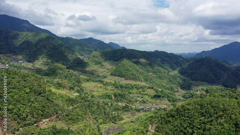 A village emerges from the green rice fields, in Asia, in the Philippines, in Ifugao, in Luzon, towards Banaue, in summer, on a sunny day. A village emerges from the green rice fields, in Asia, in the Philippines, in Ifugao, in Luzon, towards Banaue, in summer, on a sunny day.