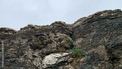 Rugged rocky cliff under cloudy sky, perfect for exploring nature, adventure themes, or Earth Day celebrations