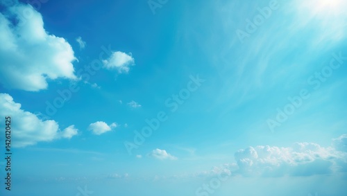 Fototapeta Naklejka Na Ścianę i Meble -  The tranquil bright blue sky features gentle white clouds drifting peacefully under soft sunlight, creating a calming and refreshing ambiance.