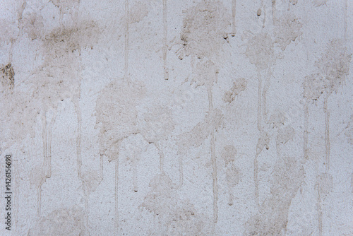 A grey wall with stains in the form of paint drips. Splashes of dirt cover the wall.