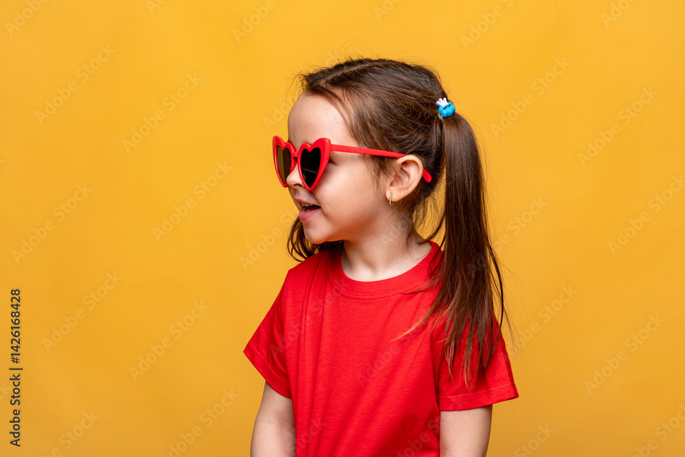 Side view smiling little child girl dressed in red t-shirt and red funny sunglasses on yellow studio background. Summer travel vacation with children, advertising concept. Banner, mock up, copy space