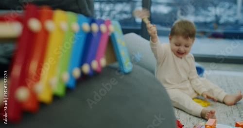 A baby explores toys while a child plays a xylophone, showcasing joy
