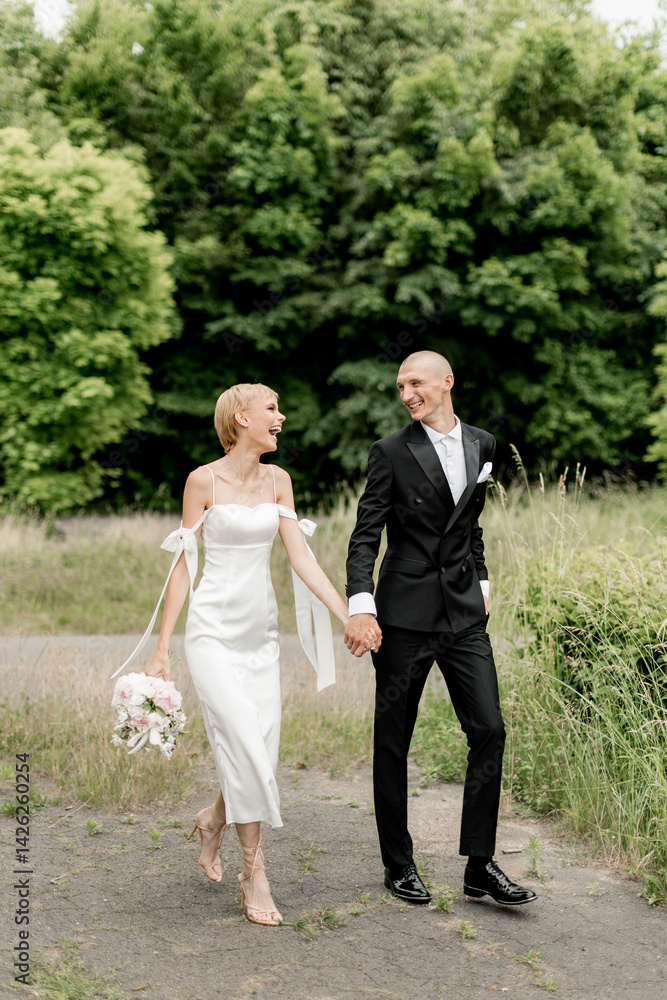 Beautiful wedding couple walking in the park holding hands Beautiful wedding couple walking in the park holding hands