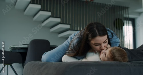 A mother lovingly interacts with her baby on the couch, sharing moments