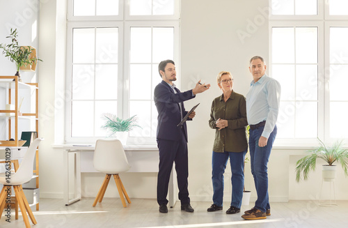 Realtor, real estate agent, broker represents senior sellers or buyer new property, clients during meeting looking at room, showing apartment, planning work, having discussion with engineer, architect