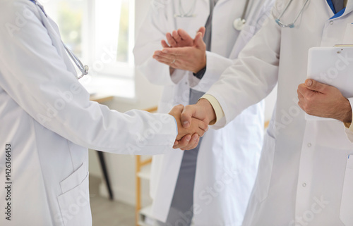Obraz na płótnie Close up cropped view of two professional doctors in white lab coats shaking hands in clinic. Medical staff exchanging handshake and applauding, celebrating teamwork or success in patient treatment. w salonie