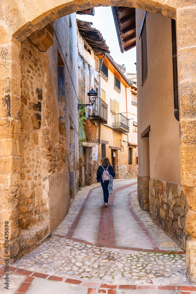 Tourist woman strolling through the picturesque streets of the beautiful medieval town of Beceite, Teruel.
