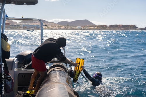 Scuba diving instructor helping diver remove fins after dive