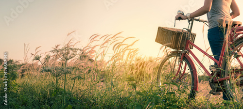 Woman with bicycle on meadow at sunset