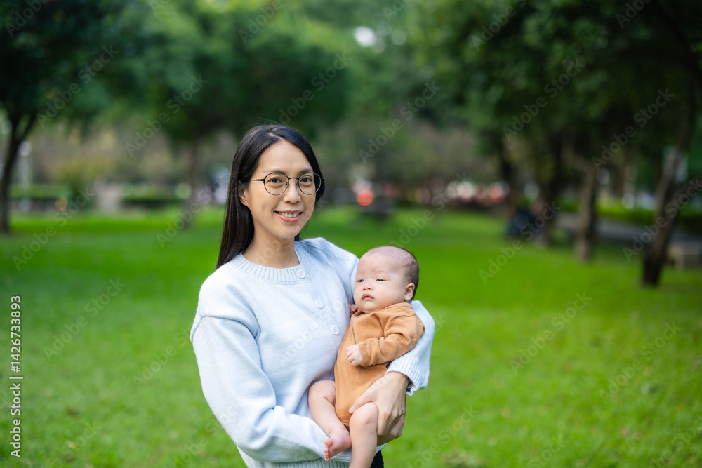 Mother holding newborn baby in park during daytime