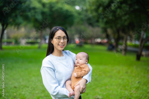 Mother holding newborn baby in park during daytime