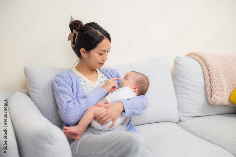 Caring mother soothing baby with pacifier at home