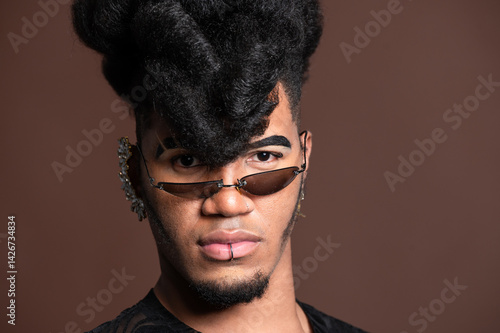 Canvas Print Young man with extravagant hairstyle and sunglasses posing in studio
