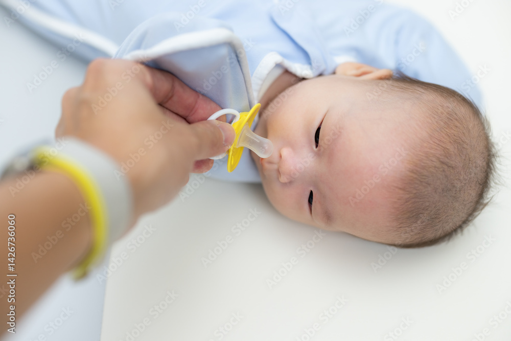 Parent offering pacifier to calm newborn baby