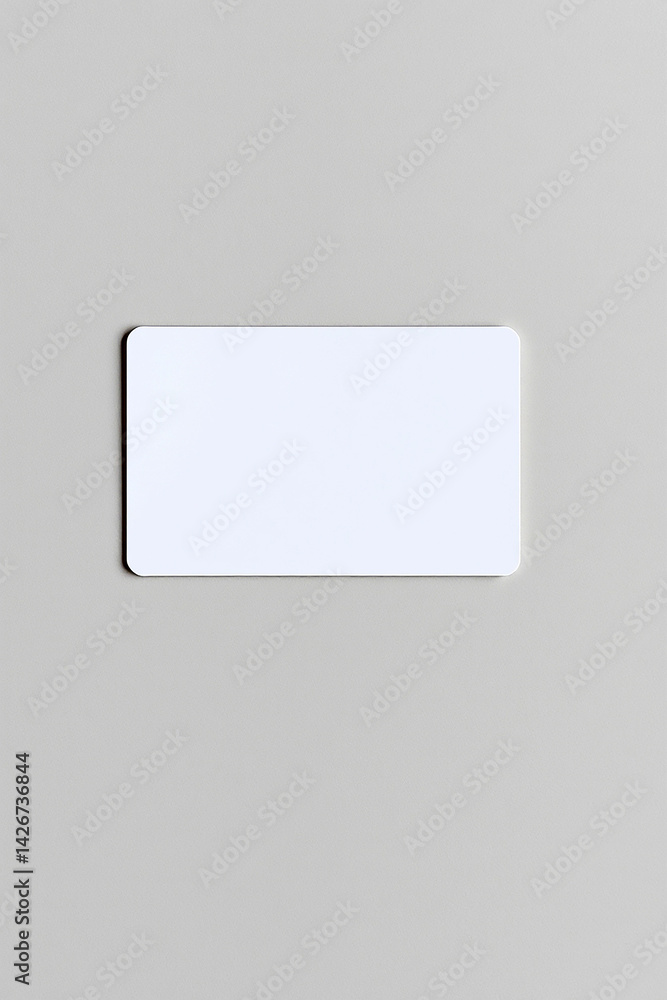 Blank white card on light grey surface. Clean rectangular object with rounded corners. Simple template for message. Minimal presentation of plain card. Rectangular shape displayed on plain backdrop. Blank white card on light grey surface. Clean rectangular object with rounded corners. Simple template for message. Minimal presentation of plain card. Rectangular shape displayed on plain backdrop.