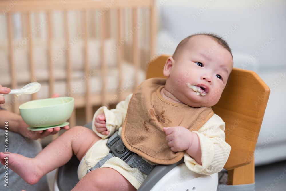 Baby on high chair eating food happily