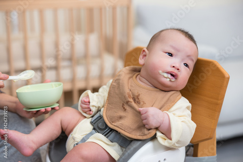 Obraz na płótnie Baby on high chair eating food happily w salonie