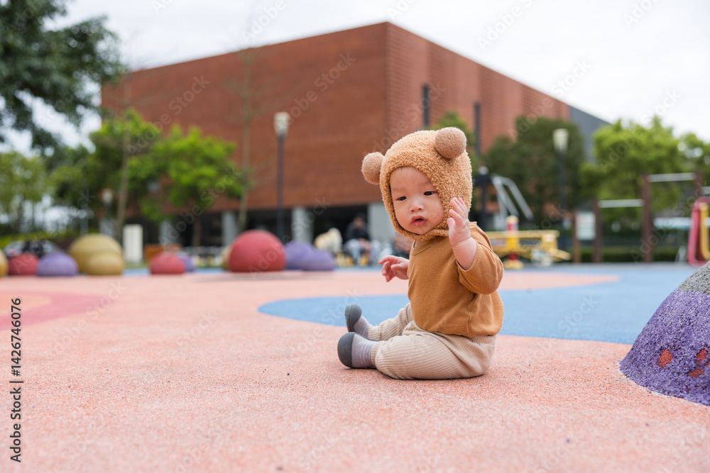 Baby sitting on grass wearing cute bear hat