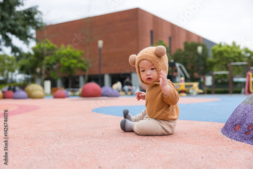 Obraz na płótnie Baby sitting on grass wearing cute bear hat w salonie