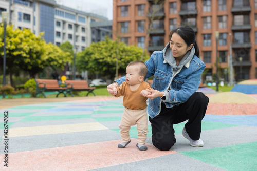 Baby walking with mother at colorful park