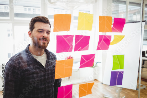Obraz na płótnie Young man studying multicolored sticky notes on glass partition in modern office, copy space w salonie