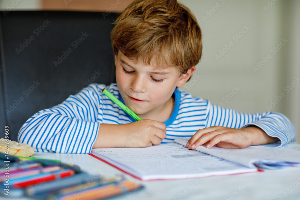 Portrait of cute healthy happy school kid boy at home making homework. Little child writing with colorful pencils, indoors. Elementary school and education. Kid learning writing letters and numbers