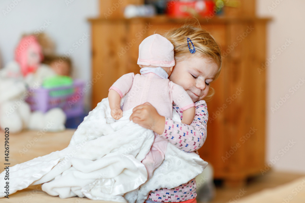 Adorable cute little toddler girl playing with doll. Happy healthy baby child having fun with role game, playing mother at home or nursery. Active daughter with toy.