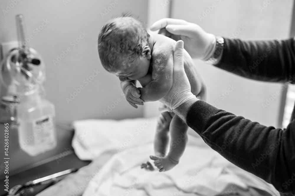 Newborn child seconds and minutes after birth. Doctor hands with new born baby. Medical check up of health and reflexes of child. New life, beginning, healthcare