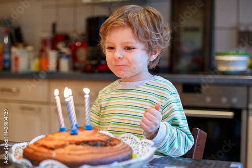 Obraz na płótnie Adorable four year old boy celebrating his birthday and blowing off the candles on the cake, indoor. Happy child with big cake. w salonie