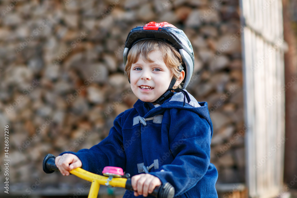 Little boy riding bicycle in village or city. Happy preschool child on balance bike, having fun. Outdoor leisure and games for children.