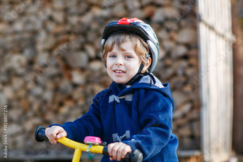 Obraz na płótnie Little boy riding bicycle in village or city. Happy preschool child on balance bike, having fun. Outdoor leisure and games for children. w salonie
